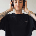 Frau mit Kopfhörer auf, die das oversized shirt love in der Farbe schwarz trägt.