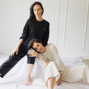 Zwei Frauen, die sich aneinander anlehnen. Ein Frau trägt das oversized shirt trust in der Farbe ecru (ungefärbte Baumwolle) trägt. Die andere Frau trägt das oversized shirt trust in schwarz.