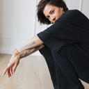 Frau die kniet und das oversized shirt trust in schwarz trägt.