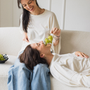 Zwei Frau die lachen, weil die eine Frau von der anderen Frau mit Weintrauben gefüttert wird. Sie tragen beid das oversized shirt joy in der Farbe ecru (ungefärbte Baumwolle).
