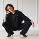 Frau die selbstbewusst kniet und das oversized shirt trust in schwarz trägt.