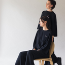 Zwei Frauen - eine sitzt, die andere steht hinter ihr - blicken in die Ferne. Sie tragen dabei das oversized shirt peace in der Farbe schwarz.